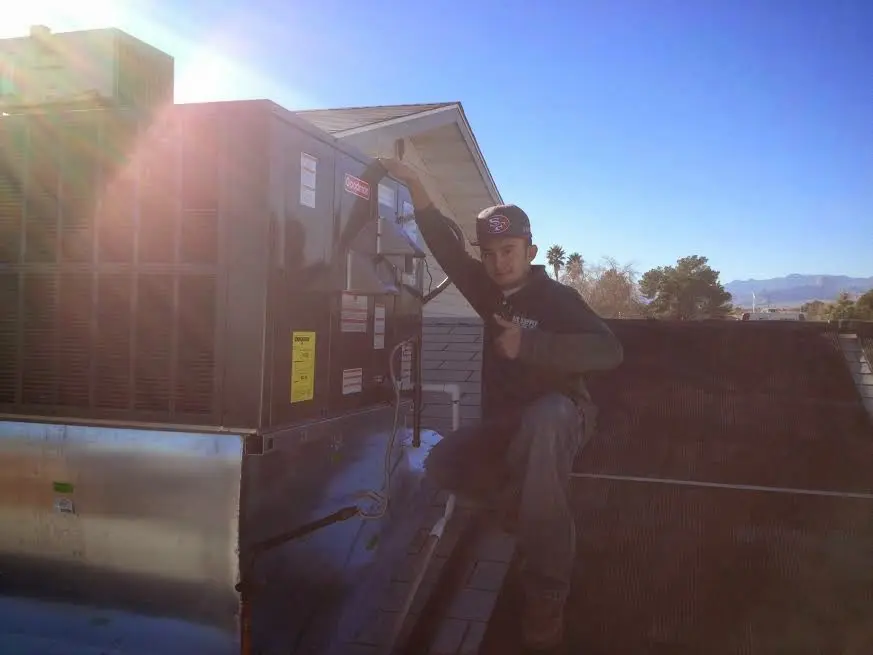 HVAC technician performing Air Duct Cleaning on a rooftop unit in Slinger